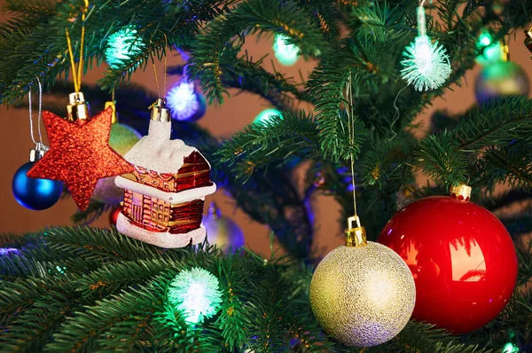 Maison, boules, étoiles et guirlande d'éclairage sur l'arbre de Noël — Photo