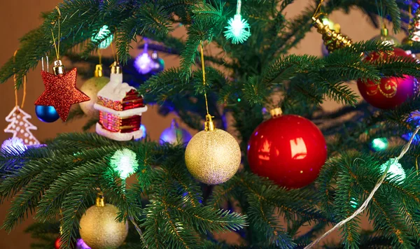 Casa, bolas, estrellas y guirnalda de iluminación en el árbol de Navidad —  Fotos de Stock