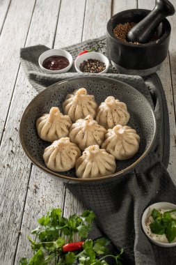 Close up to Caucasian khinkali dumplings dish served on plate. Background with ingredients and scattered spices