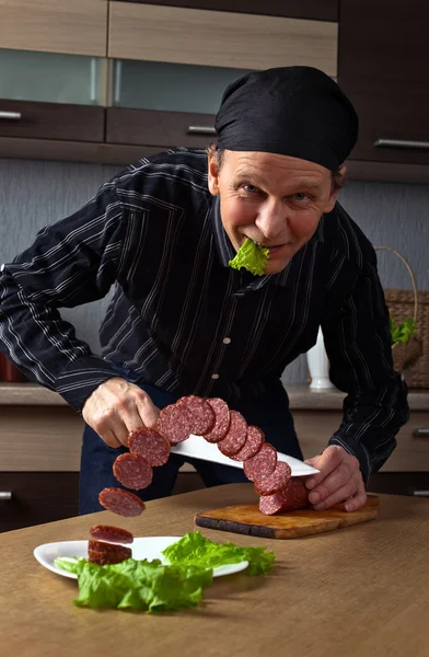 Mann schneidet Wurst auf — Stockfoto