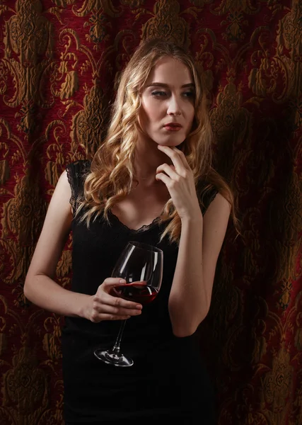 Piękna kobieta w czarnej sukni z czerwonym winem — Zdjęcie stockowe