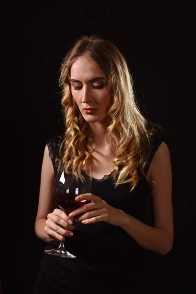 Hermosa rubia en vestido negro con copa de vino tinto — Foto de Stock