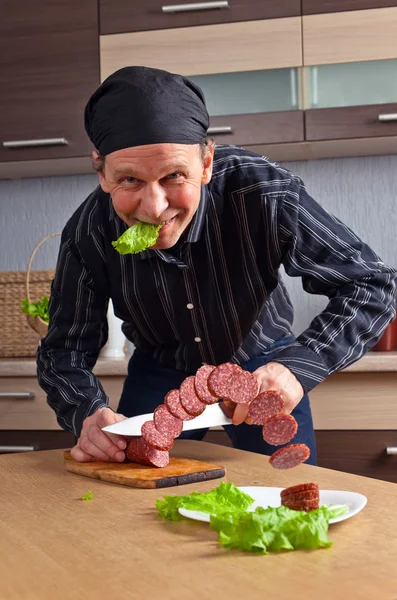 Мужчина режет колбасу — стоковое фото