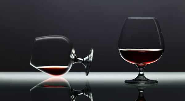 Два глотка бренди на стеклянном столе — стоковое фото
