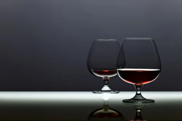 Two snifters of brandy on glass table — Stock Photo, Image