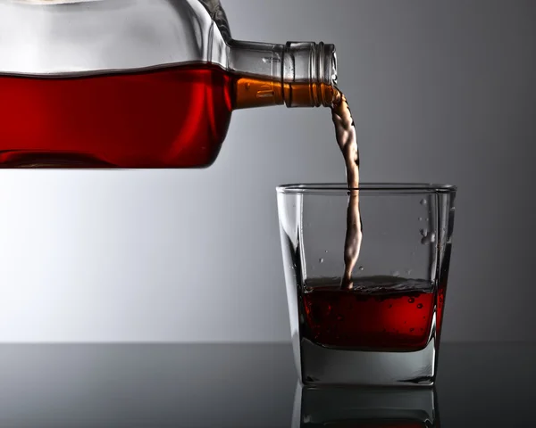 Бутылка и стакан виски на стеклянном столе — стоковое фото