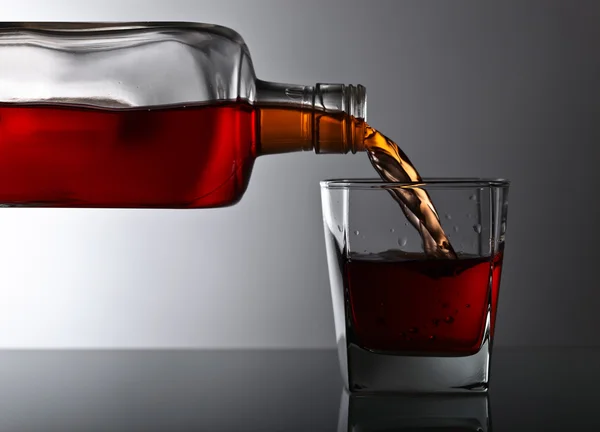 Bottiglia e bicchiere di whisky su un tavolo di vetro — Foto Stock