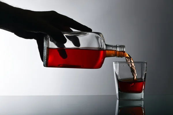 Bouteille et verre de whisky sur une table en verre — Photo