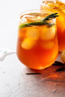 Limonlu, limonlu ve biberiye dallarıyla süslenmiş geleneksel buzlu çay. Turunçgil dilimli donmuş bardaklar..