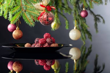 Siyah tabakta çeşitli çikolatalı mantarlar ve Noel ağacı..