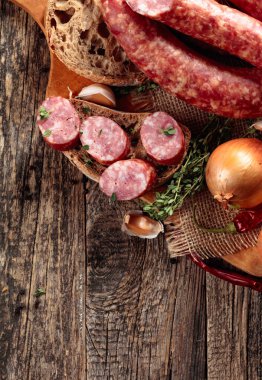 Kurutulmuş sosis ve baharatlı otlar. Ekmek, kekik, biber, soğan ve sarımsaklı sosisler eski ahşap bir masada. Basit sağlıklı yiyecekler. Boşluğu kopyala.