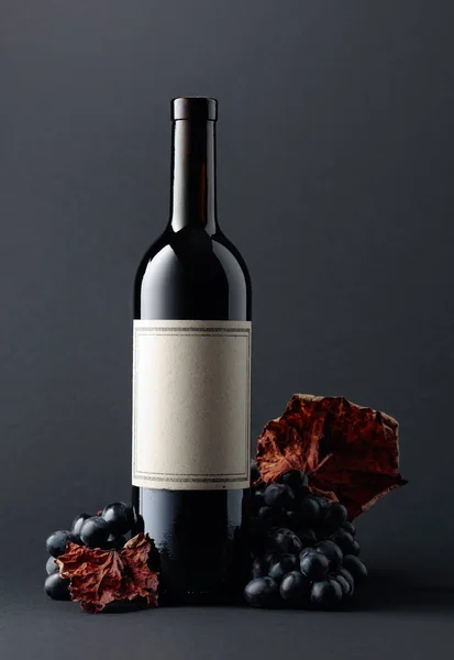Μπουκάλι Κόκκινο Κρασί Και Μπλε Σταφύλια Αποξηραμένα Αμπελόφυλλα Σκούρο Φόντο — Φωτογραφία Αρχείου