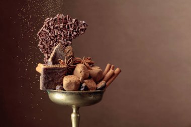 İçinde malzemeler olan çeşitli çikolatalar. Eski bir pirinç kase şeker, kahve çekirdekleri, tarçın, anason ve kırık siyah çikolata parçalarında. Boşluğu kopyala.