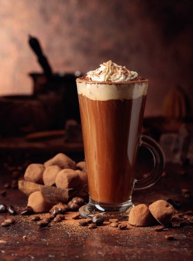 Yer mantarı ve kremalı bir bardak sıcak çikolata. Tatlı ve içecek Eski kahverengi bir masanın üzerine kakao tozu serpiştirilmiş.