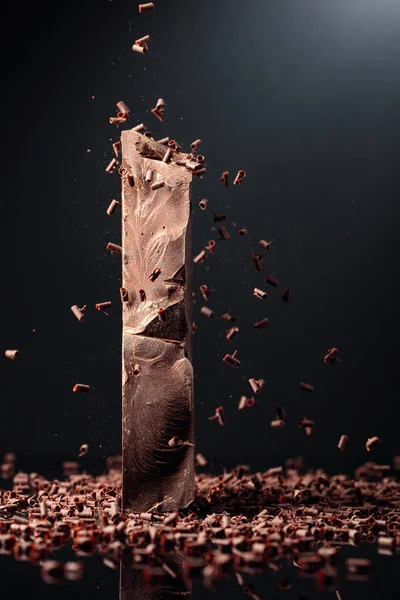 Stor Bit Mörk Choklad Och Fallande Chokladsmulor Svart Bakgrund — Stockfoto