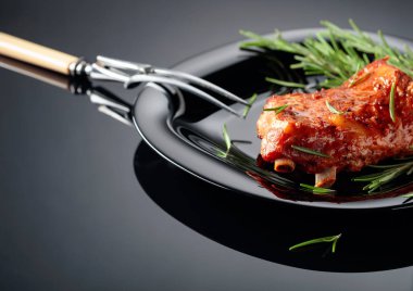 Siyah tabakta ızgara domuz pirzolası. Siyah zemin üzerine biberiye serpiştirilmiş ızgara et..