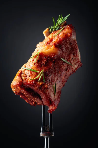 フォークの上で豚カルビを焼きます 黒い背景にローズマリーを振りかけた焼き肉 — ストック写真