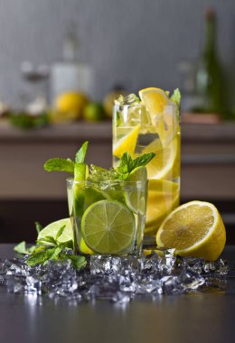 Limon, limon, buz ve nane yapraklı kokteyller siyah bir masada. .