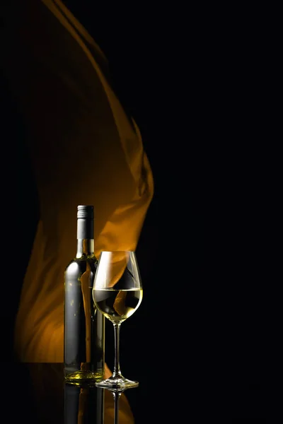 Бутылка Бокал Белого Вина Черном Отражающем Фоне Желтая Ткань Трепещет — стоковое фото