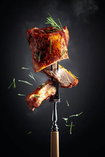 フォークの上で豚カルビを焼きます 黒い背景にローズマリーを振りかけた焼き肉 — ストック写真