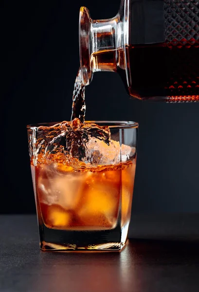 ウイスキーは天然氷で覆われたガラスに注ぐ アルコール飲料はクリスタルデカンタからガラスに注がれます — ストック写真
