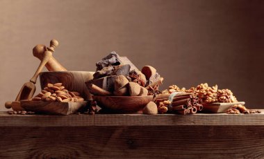 İçinde malzemeler olan çeşitli çikolatalar. Eski ahşap masa şekerleri, kahve çekirdekleri, tarçın, anason, fındık ve kırık siyah çikolata parçaları.. 