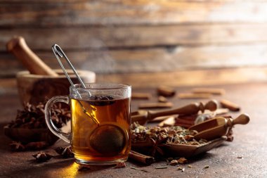 Tarçınlı, anasonlu ve kurutulmuş otlu Noel çayı. Eski kahverengi bir masada, ahşap tabaklarda baharatlı bitki çayı..