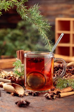 Tarçınlı, anasonlu ve kurutulmuş otlu Noel çayı. Kahverengi bir masada ardıç dallı bitki çayı..