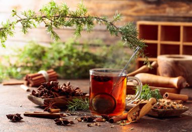 Tarçınlı, anasonlu ve kurutulmuş otlu Noel çayı. Kahverengi bir masada ardıç dallı bitki çayı..