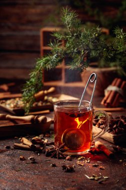 Tarçınlı, anasonlu ve kurutulmuş otlu Noel çayı. Kahverengi bir masada ardıç dallı bitki çayı..