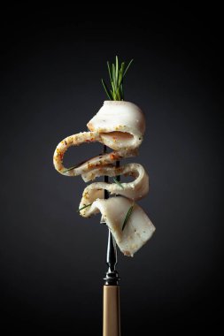 Çatalda tuzlanmış baharatlı domuz yağı. Siyah arka planda biberiyeli domuz yağı..