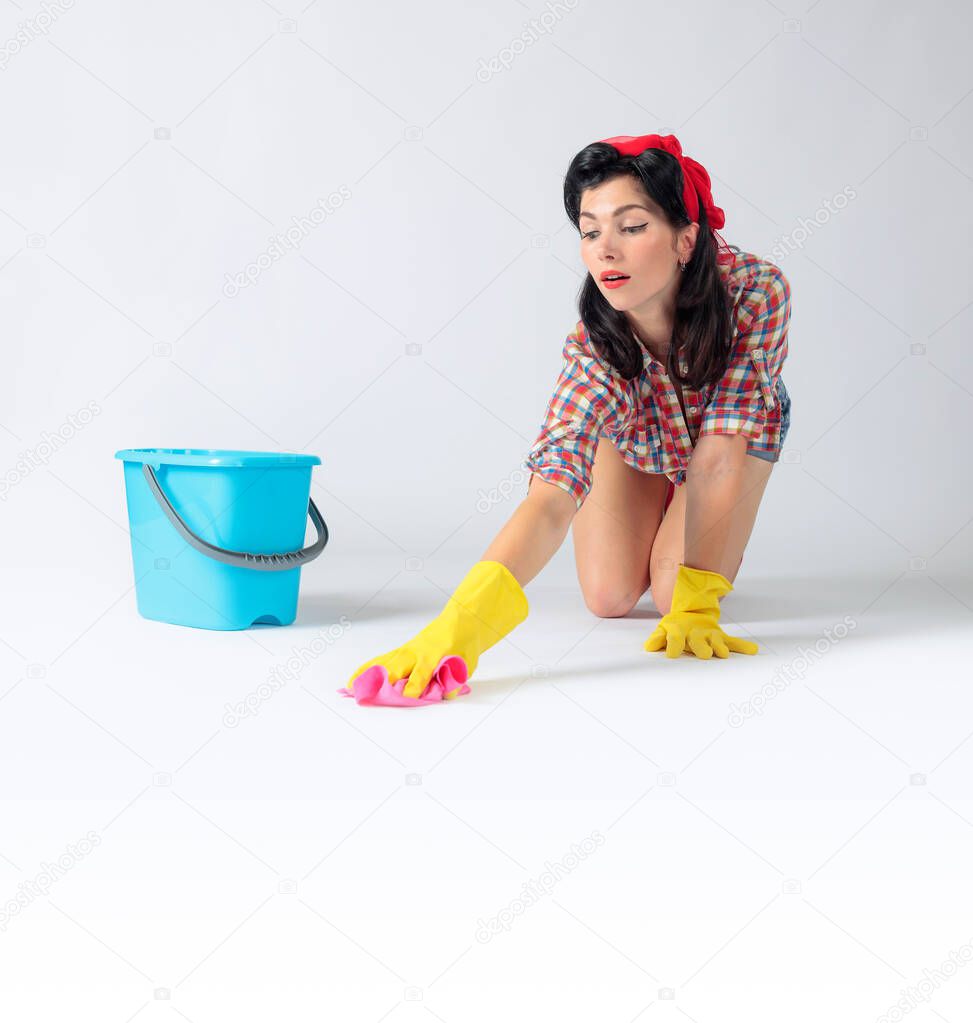 Smiling girl in rubber gloves wash the floor with rag and detergent. Copy space for your text.
