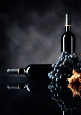 Kırmızı şarap ve siyah yansıtıcı arka planda bir demet üzüm. Seçici odak.