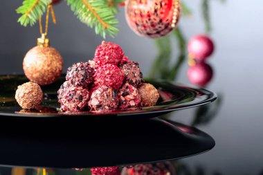 Siyah tabakta çeşitli çikolatalı mantarlar ve Noel ağacı..