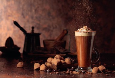 Yer mantarı ve kremalı bir bardak sıcak çikolata. Tatlı ve içecek Eski kahverengi bir masanın üzerine kakao tozu serpiştirilmiş.