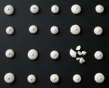 Siyah masanın üzerinde küçük beyaz kremalar. Yukarıdan görünüşü.