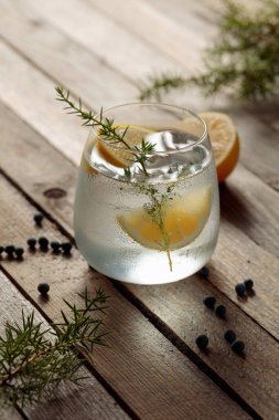 Limonlu alkol içeceği (cin tonik kokteyli), ardıç dalı ve kırsal ahşap masa üzerindeki buz, kopyalama alanı. Limonlu buzlu kokteyl..