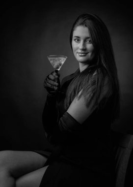 Yeşil zeytinli sek martini içen çekici bir kız. Güzel esmer, elinde bardakla soğuk bir kokteyl tutuyor. Siyah ve beyaz.