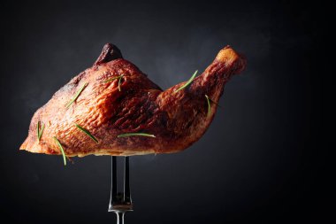 Biberiye serpilmiş çatalla tütsülenmiş tavuk budu. Siyah arka planda sıcak tavuk. Boşluğu kopyala.