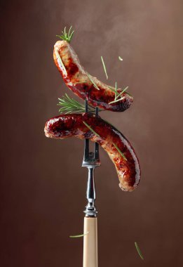 Biberiyeli ızgara Bavyera sosisi. Biberiye serpilmiş çatallı sosisler. Kahverengi arkaplan.