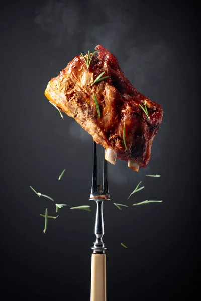 叉子上烤猪排 用迷迭香撒在黑色背景上的烤肉 — 图库照片