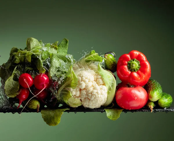 有水花的各种生蔬菜 花椰菜 西红柿 萝卜和红辣椒 绿色背景 — 图库照片