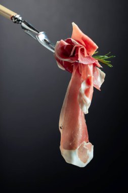 Çatal üzerinde biberiyeli dilimlenmiş jambon, siyah arkaplan, boşluğu kopyala.