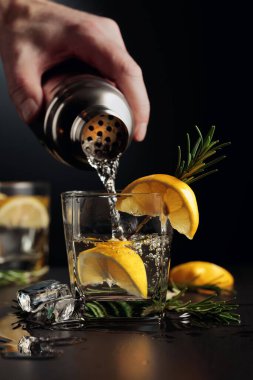 Limonlu ve biberiyeli kokteyl Cin ve Tonik. Barmen bardaktan bardağa kokteyl doldurur..