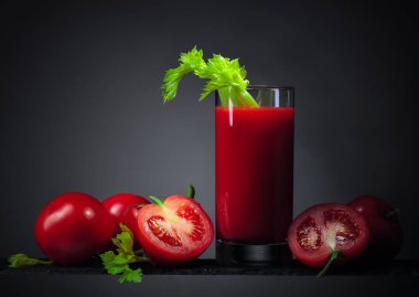 Domatesli domates suyu ve koyu arkaplanda kereviz çubukları..