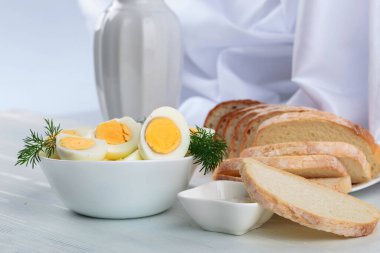 Beyaz ahşap bir masada ekmek ve tuzlu haşlanmış yumurta..