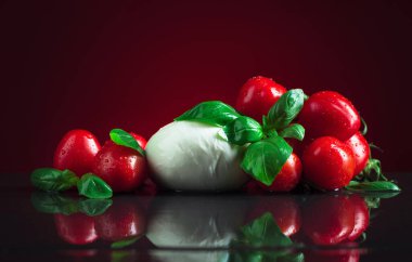 Siyah bir masada yeşil fesleğenli ve domatesli Mozzarella..