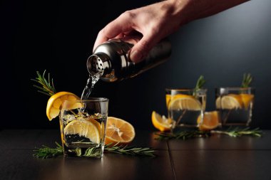 Limonlu ve biberiyeli kokteyl Cin ve Tonik. Barmen bardaktan bardağa kokteyl doldurur..