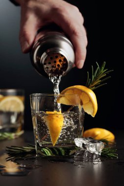 Limonlu ve biberiyeli kokteyl Cin ve Tonik. Barmen bardaktan bardağa kokteyl doldurur..