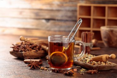 Tarçınlı, anasonlu ve kurutulmuş otlu Noel çayı. Eski kahverengi bir masada, ahşap tabaklarda baharatlı bitki çayı..